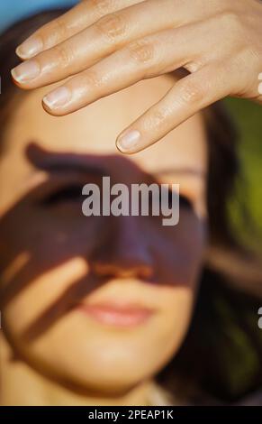 Nahaufnahme einer jungen Frau, die die Augen abschirmt Stockfoto