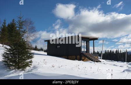 Blick auf eine moderne kleine Hütte auf dem verschneiten Berg in der Ukraine Stockfoto