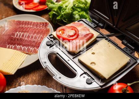 Sandwichmacher. Sandwiches mit verschiedenen Füllungen zubereiten. Stockfoto