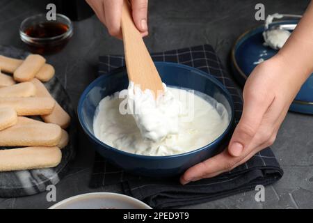 Eine Frau, die Tiramisu-Kuchen am schwarzen Tisch macht, Nahaufnahme Stockfoto