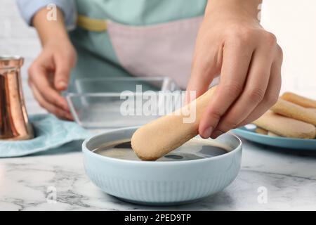 Eine Frau, die Tiramisu-Kuchen am weißen Marmortisch macht, Nahaufnahme Stockfoto