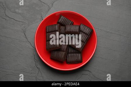 Roter Teller mit köstlichem und gesundem Hämatogen auf schwarzem Tisch, Draufsicht Stockfoto