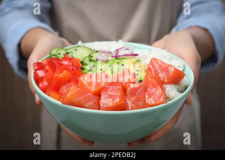 Eine Frau, die eine köstliche Schüssel mit Lachs und Gemüse hält, Nahaufnahme Stockfoto