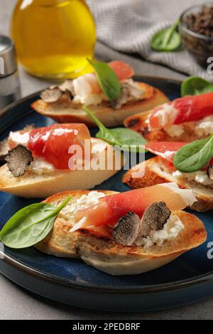 Köstliche Bruschettas mit Käse, Prosciutto und Scheiben von schwarzen Trüffeln auf dem Tisch, Nahaufnahme Stockfoto