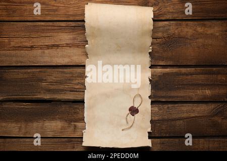 Blatt altes Pergamentpapier mit Wachsstempel auf Holztisch, Draufsicht. Raum für Design Stockfoto