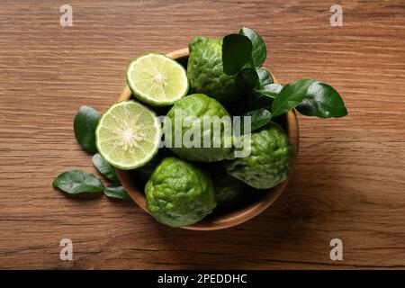 Frische reife Bergamotte-Früchte mit grünen Blättern auf einem Holztisch, Draufsicht Stockfoto