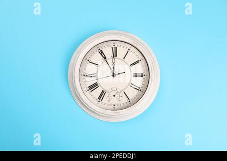 Stilvolle Wanduhr mit fünf Minuten bis Mitternacht auf türkisfarbenem Hintergrund, Draufsicht. Der Countdown für das neue Jahr Stockfoto