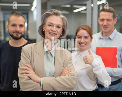 Porträt von vier Büroangestellten. Eine grauhaarige, reife Frau, ein weißer Mann, ein bärtiger Mann und eine rothaarige Frau. Stockfoto