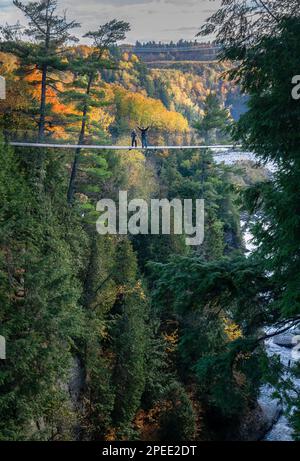 Touristen stehen auf einer von zwei Hängebrücken, die sich über die Tiefen des Canyon Sainte-Anne erstrecken. Quebec. Kanada. Vertikales Format. Stockfoto