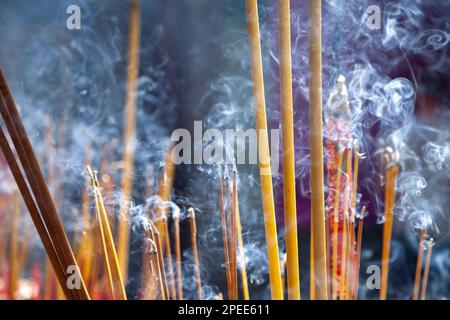 Viele duftende Räucherstäbchen brennen in einem buddhistischen Schrein und schaffen eine duftende und rauchige Atmosphäre. Die Verwendung von Weihrauch in Meditation und Entspannung ist Stockfoto