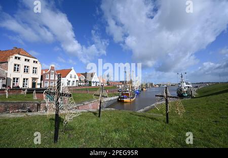 Greetsiel, Deutschland. 15. März 2023. Schwarze Kreuze mit Netzen sind ein stiller Protest der Fischer am Hafen. Die hölzernen Kreuze sollen zur Zeit die Aufmerksamkeit auf eine unmittelbare Gefahr an vielen Küstenorten in Norddeutschland lenken: Die Fischer haben sie errichtet, weil sie das Ende ihrer Industrie fürchten. Konkret geht es um ein geplantes Verbot von so genannten Grundschleppnetzen. Kredit: Lars Klemmer/dpa/Alamy Live News Stockfoto