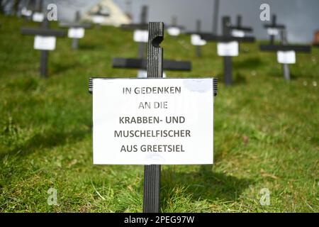 Greetsiel, Deutschland. 15. März 2023. Schwarze Kreuze sind ein stiller Protest der Fischer auf dem Deich im Hafen. Die hölzernen Kreuze sollen zur Zeit die Aufmerksamkeit auf eine unmittelbare Gefahr an vielen Küstenorten in Norddeutschland lenken: Die Fischer haben sie errichtet, weil sie das Ende ihrer Industrie fürchten. Konkret geht es um ein geplantes Verbot von so genannten Grundschleppnetzen. Kredit: Lars Klemmer/dpa/Alamy Live News Stockfoto