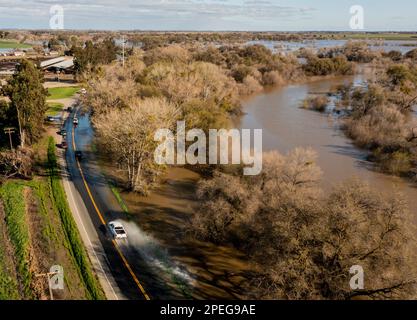 Grayson, Kalifornien, USA. 15. März 2023. Autos fahren auf der Grayson Road vom San Joaquin River aus durch Flutwasser Mittwoch, 15. März 2023 Nachmittag. Die Straße wurde schließlich aufgrund der Gefahr gesperrt. Erhöhte Werte im Fluss führten zu Flüssen über seine Ufer, Überschwemmungen eines lokalen Parks und Ackerland. Das kalifornische Hochwasser steigt weiter an, da der Bundesstaat kaum von Regen und Schnee befreit war. Mittwoch, 15. März 2023 Mutter Natur gab dem Staat eine Pause, so dass sich viele Gebiete erholten und mit der zunehmenden Überschwemmung und den ansteigenden Flüssen zurechtkamen. Kredit: ZUMA Press, Inc./Alamy Live News Stockfoto