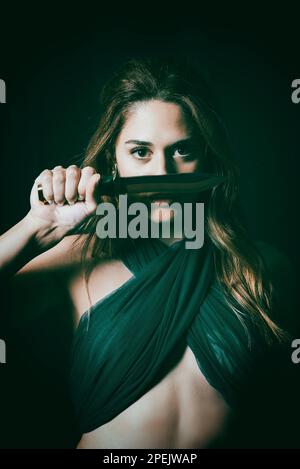 Eine gefährliche, schöne Frau, die ein Messer in der Hand hält Stockfoto