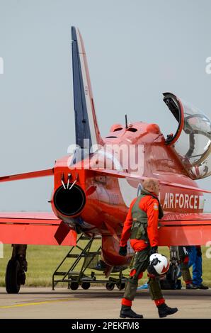 Die Roten Pfeile der Royal Air Force zeigen den Teampiloten (verschwommen), der vor der Ausstellung zum Düsenflugzeug BAE Hawk T1, RAF Scampton, geht. Rauchrohre über dem Auspuff Stockfoto