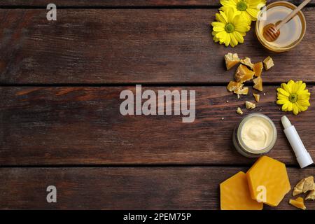 Flachliegenzusammensetzung mit Bienenwachs und kosmetischen Mitteln auf Holztisch. Platz für Text Stockfoto