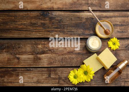 Flachliegenzusammensetzung mit Bienenwachs und kosmetischen Mitteln auf Holztisch. Platz für Text Stockfoto