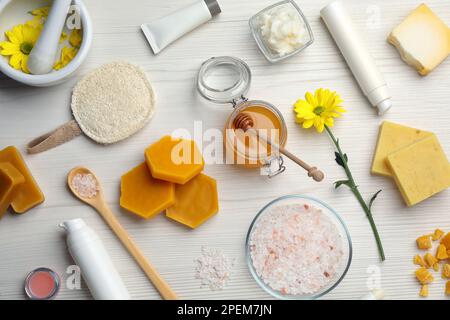 Flache Laienzusammensetzung mit Bienenwachs und kosmetischen Mitteln auf weißem Holztisch Stockfoto