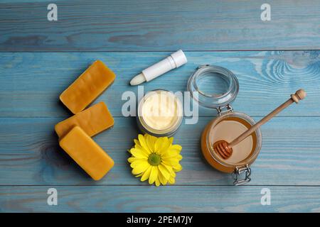 Flache Laienzusammensetzung mit Bienenwachs und kosmetischen Mitteln auf blauem Holztisch Stockfoto