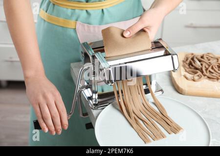 Eine Frau, die Soba (Buchweizennudeln) zubereitet, mit einer Nudelmaschine in der Küche, Nahaufnahme Stockfoto