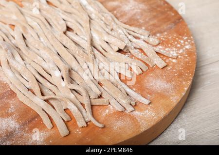 Ungekochtes hausgemachtes Soba (Buchweizennudeln) auf Holztisch, Nahaufnahme Stockfoto