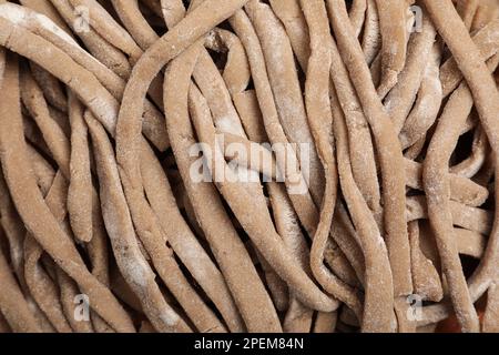 Ungekochtes hausgemachtes Soba (Buchweizen-Nudeln) im Hintergrund, Draufsicht Stockfoto