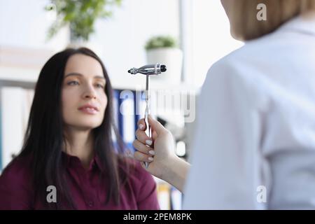 Neurologe prüft Reflexe mit Spezialhammer bei der Untersuchung einer jungen Patientin in der Praxis Stockfoto