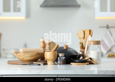 Set aus Kochutensilien und Produkten auf weißem Tisch vor verschwommenem Hintergrund Stockfoto