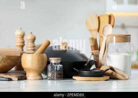 Set aus Kochutensilien und Produkten auf weißem Tisch vor verschwommenem Hintergrund Stockfoto