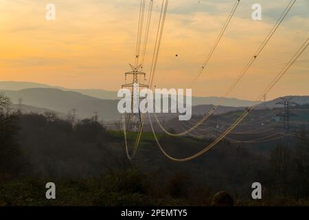 Hochspannungsleitungen bei Sonnenuntergang. Elektrizitätsverteilungsstation. Hochspannungs-Stromübertragungsmast. Stockfoto