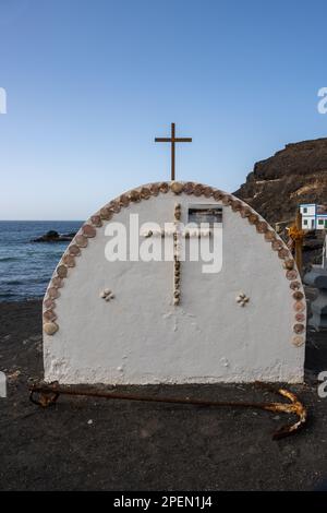 Denkmal an einer Küste des Atlantischen Ozeans. Kante und Kreuz aus Muscheln. Ein alter Anker davor. Los Molinos, Fuerteventura, Kanarische Inseln, Spa Stockfoto