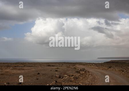 Hellbrauner Boden, voller Steine und Felsen an der Westküste der Insel an der Küste des Atlantischen Ozeans. Intensive Wolken im Winter. Westküste (A Stockfoto