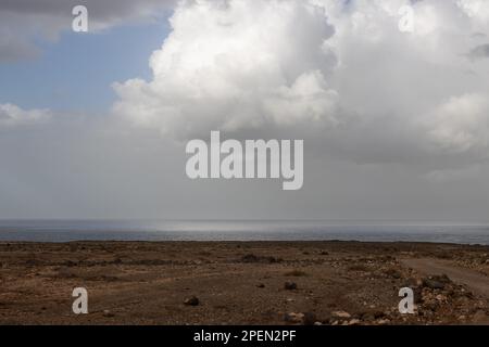 Hellbrauner Boden, voller Steine und Felsen an der Westküste der Insel an der Küste des Atlantischen Ozeans. Intensive Wolken im Winter. Westküste (A Stockfoto