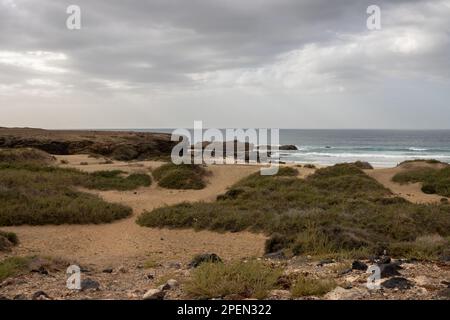 Hellbrauner Boden, voller Steine und Felsen an der Westküste der Insel an der Küste des Atlantischen Ozeans. Intensive Wolken im Winter. Westküste (A Stockfoto