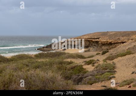 Hellbrauner Boden, voller Steine und Felsen an der Westküste der Insel an der Küste des Atlantischen Ozeans. Intensive Wolken im Winter. Westküste (A Stockfoto