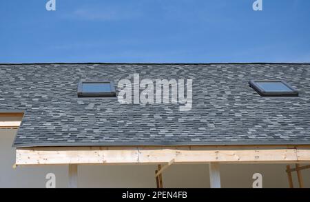 Dachhausbau mit neuen Dachfenstern und Asphaltschindeln. Stockfoto