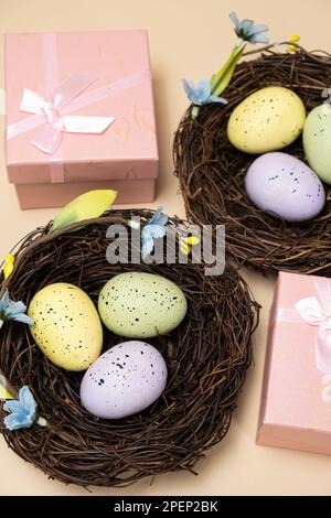 Geschenke zu Ostern, Osterverkauf. Eier in Nestern und Geschenkschachteln auf beigefarbenem Hintergrund. Stockfoto