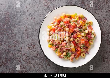 Gesunde Lebensmittel Vorspeisensalat aus Kichererbsen, Paprika, Oliven, Tomaten, grünen Zwiebeln und Amaranth Mikrogreens und Samen Nahaufnahme auf einem Teller auf dem Tisch Stockfoto