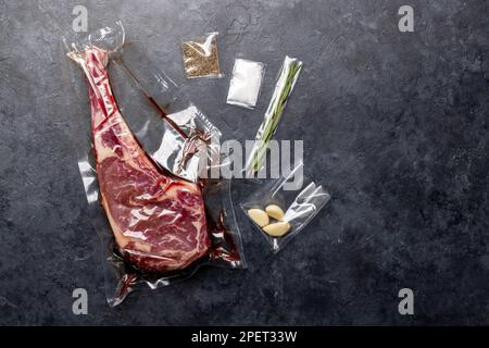 Rohes Tomahawk-Rindersteak, vakuumverpackt und Gewürze. Bereit zum Grillen. Flach verlegt Stockfoto