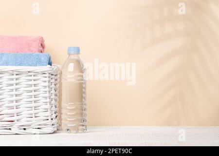 Wasserflasche und Badhandtücher auf dem Tisch mit Platz für Ihr Produkt oder Text. Spa-Arrangement Stockfoto