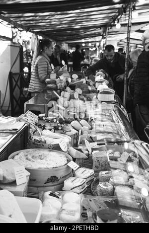 Saint-Maur-des-Fosses, Frankreich - 8. Oktober 2022: Die Menschen kaufen Käse und andere Milchprodukte von einem Käsesaal auf einem Straßenbauernmarkt. Schwarz-weiß Stockfoto