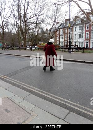 Ältere Dame überquert eine Straße in London, Großbritannien Stockfoto