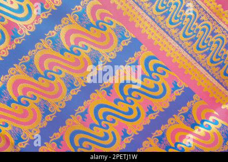Nahaufnahme: Rosafarbener, rosafarbener hintergrund aus thailändischem Seidenstoff. Thailändisches Stoffmuster ist berühmt und einzigartig. Stockfoto