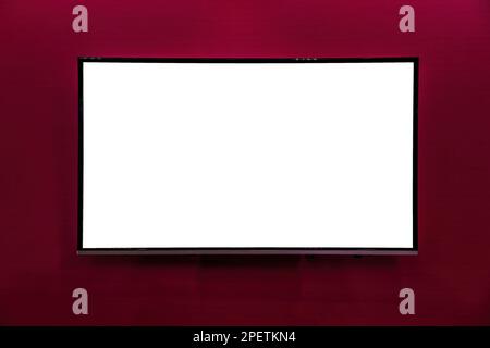 Ein Monitor mit Kopierbereich für Text, der mit roter Tapete an der Wand hängt. Modell für Konstruktion. Leeres Poster. Stockfoto