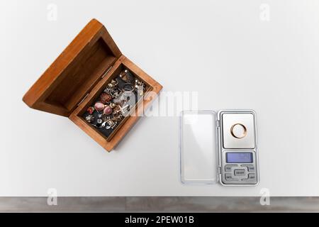 Auf dem Tisch befinden sich Waagen für kleine Gegenstände. Schmuckwaage. der goldene Ring liegt auf der Waage. Schmuckkästchen. Hochwertiges Foto Stockfoto