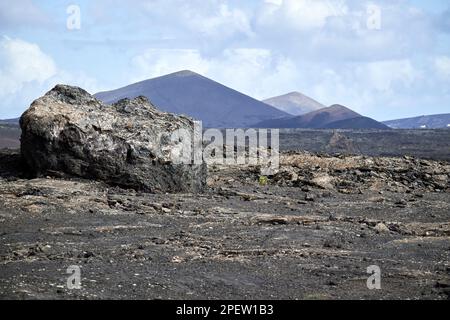 Blick über vulkanische Bomben, vulkanische Felsformationen und Lavafelder zu entfernten Vulkanen parque nacional de timanfaya Lanzarote, Kanarische Inseln, Spa Stockfoto