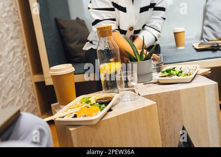 Sushi zum Mitnehmen auf kleinen Holztischen zur Mittagssszene Stockfoto