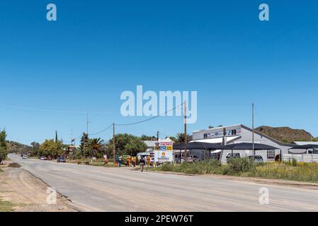 Petrusville, Südafrika – 21. Februar 2023: Eine Straßenszene mit einem Unternehmen, Fahrzeugen und Straßenwartungsmitarbeitern in Petrusville im Norden von Kap Stockfoto