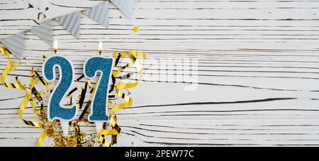 Blaue Festkerze Nummer 27 auf weißem Holzhintergrund. Alles gute zum Geburtstag, Kerzen. Konzept der Geburtstagsfeier, Jubiläumsfeier, wichtiger Termin Stockfoto