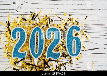 Feiertage Hintergrund Frohes neues Jahr 2026. Zahlen des Jahres 2026 aus blauen Kerzen auf festlichem weißem Holzhintergrund. Wir feiern Neujahrsfeiertage Stockfoto